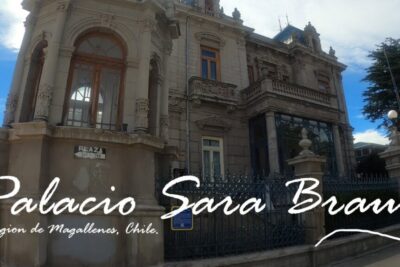 Un gran edificio histórico con una arquitectura ornamentada y rejas de hierro, el Palacio Sara Braun se erige como un legado cultural en Punta Arenas, Región de Magallanes, Chile, en un día soleado.